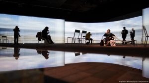 Eine flämische Küstenlandschaft wird im Pavillon der Gastregion auf halbdurchsichtige Vorhänge projiziert, die sich in einer Glasoberfläche spiegeln